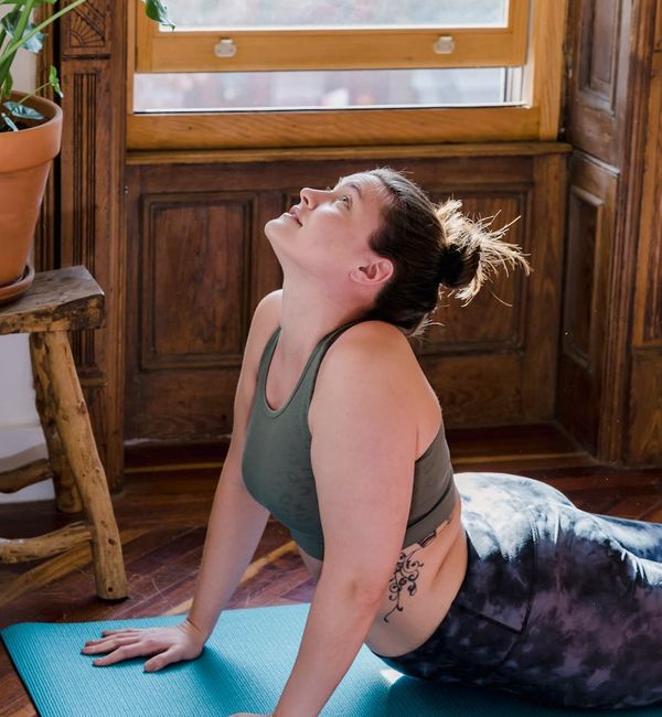 Person stretching peacefully by a large sunlit window.